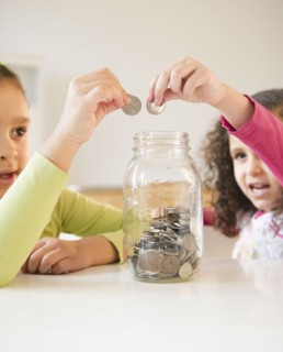 Hispanic sisters putting coins in jar