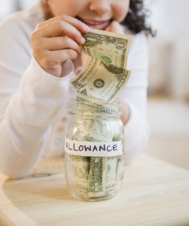 Hispanic girl putting allowance into jar