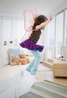 Hispanic girl in fairy wings jumping off couch