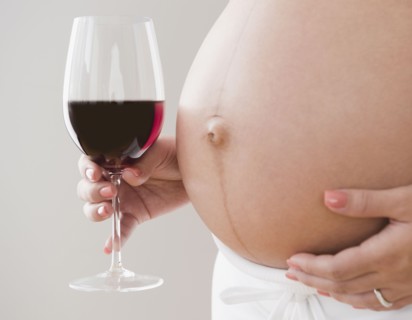 Pregnant Hispanic woman holding glass of wine