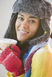 Mixed race woman in hat and gloves drinking coffee