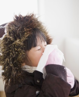 Chinese girl in coat blowing nose