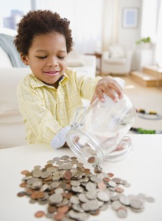 Black boy emptying jar of coins on table
