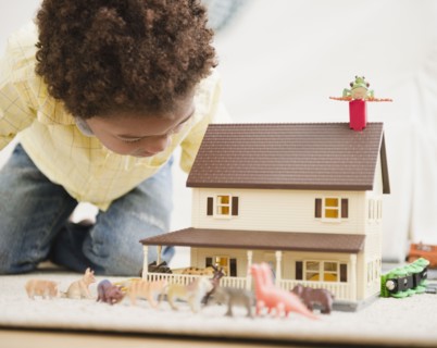 Black boy playing with toy house and animals