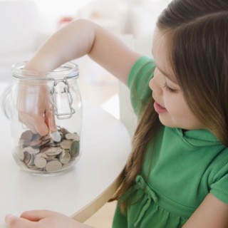 Mixed race girl taking coin out of jar
