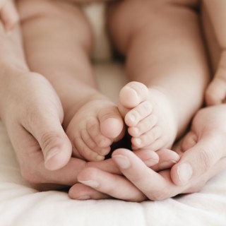Mother holding mixed race baby boy's feet