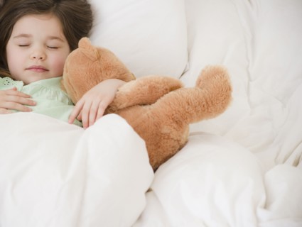 Mixed race girl sleeping with teddy bear