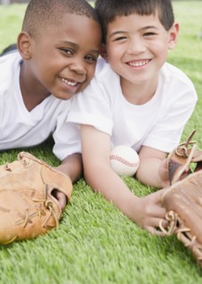 Boys laying in grass with baseball and baseball gloves