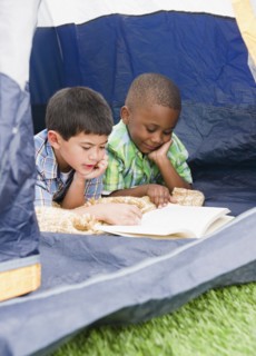 Boys reading book in tent