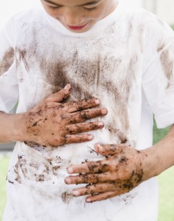 Mixed race boy wiping messy hands on shirt