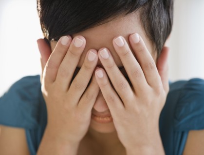 Mixed race woman covering face with hands