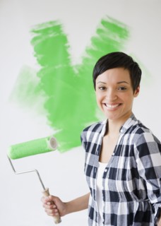 Mixed race woman holding paint roller with green paint