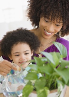 Mother and daughter watering potted plant