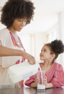 Mother pouring milk into glass for daughter