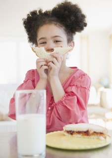 Mixed race girl holding sandwich in front of face