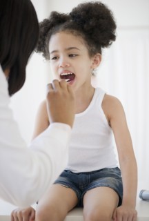 Pediatrician with tongue depressor examining patient