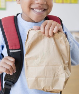 African American boy wearing backpack holding bag lunch