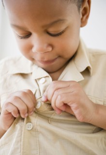 African American boy buttoning shirt