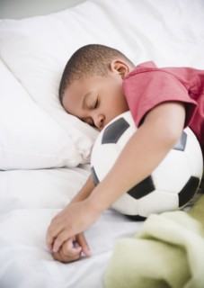 African American boy sleeping with soccer ball
