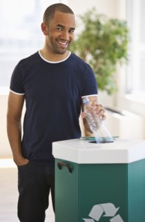 Mixed race man putting plastic bottle in recycling bin