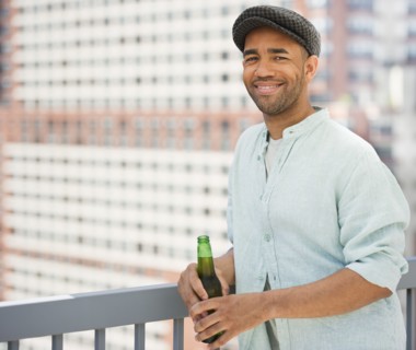 Mixed race man drinking beer near railing