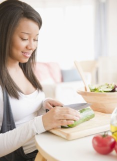 Smiling mixed race teenage girl cutting vegetables