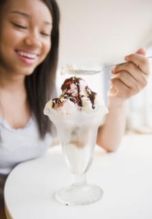 Smiling mixed race teenage girl eating ice cream sundae