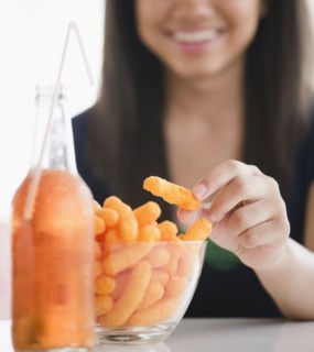 Close up of mixed race teenage girl eating cheese puffs