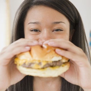 Close up of mixed race teenage girl eating cheeseburger