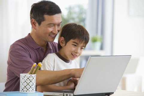 Smiling father and son using laptop