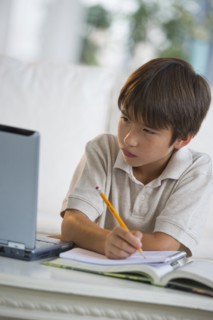 Mixed race boy doing homework and looking at laptop