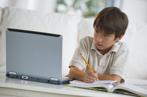 Mixed race boy doing homework and looking at laptop