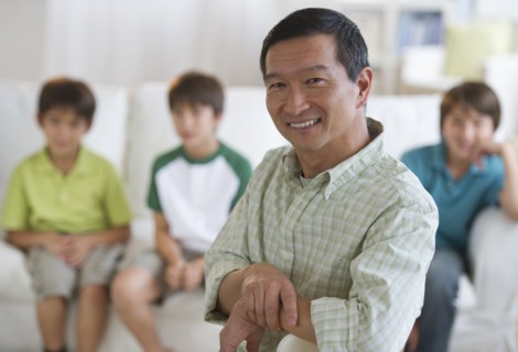 Smiling father in living room with sons in background