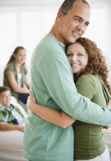 Hispanic husband and wife hugging with family in background