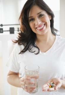 Smiling Hispanic woman taking vitamins