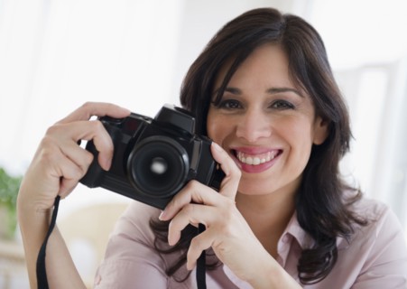 Smiling Hispanic woman holding digital camera