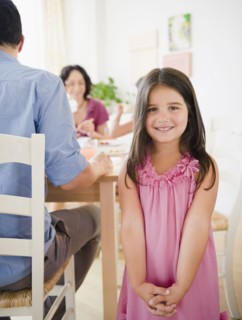 Smiling girl with family at dinner table behind her