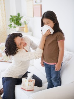 Mother wiping sick daughter's nose with tissue