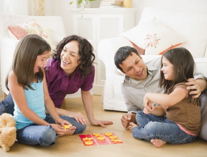 Father and mother playing game in livingroom with children