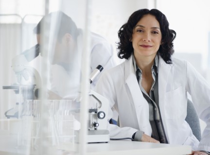 Hispanic researcher in laboratory next to microscope