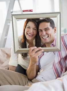 Smiling couple looking through empty frame