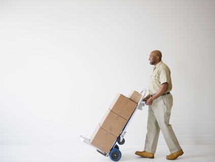 African American deliveryman pushing hand truck with boxes