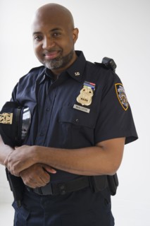 Smiling African American policeman holding cap