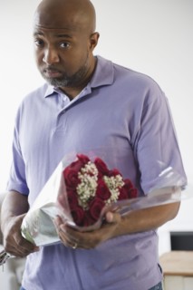 Sad African American man holding bouquet of roses