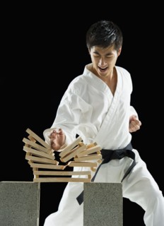 Asian male karate black belt breaking wooden planks