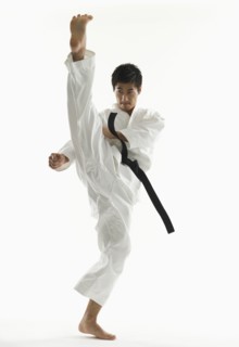 Asian male karate black belt kicking in air