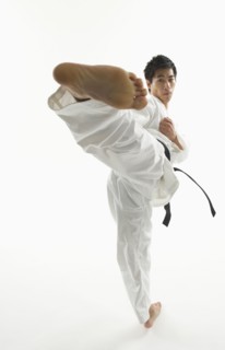 Asian male karate black belt kicking in air