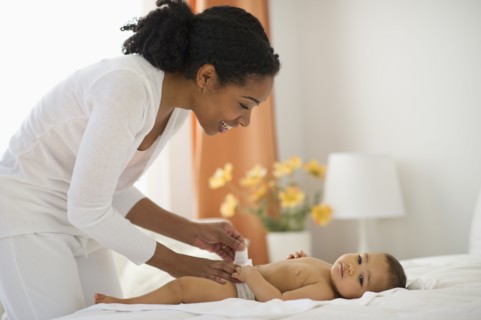 Mixed race mother changing babyÕs diaper