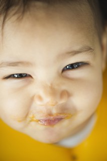 Grinning mixed race baby with messy face