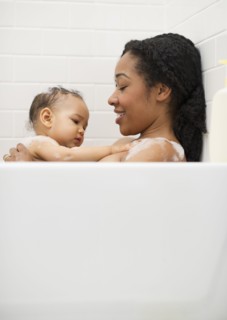 Mixed race woman bathing with baby